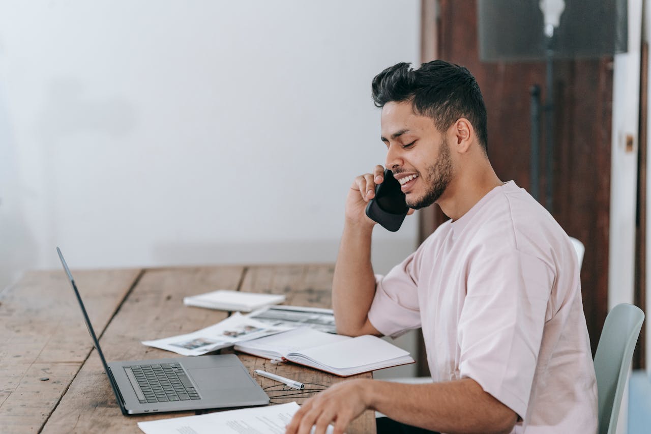 Happy businessman speaking on phone at workplace